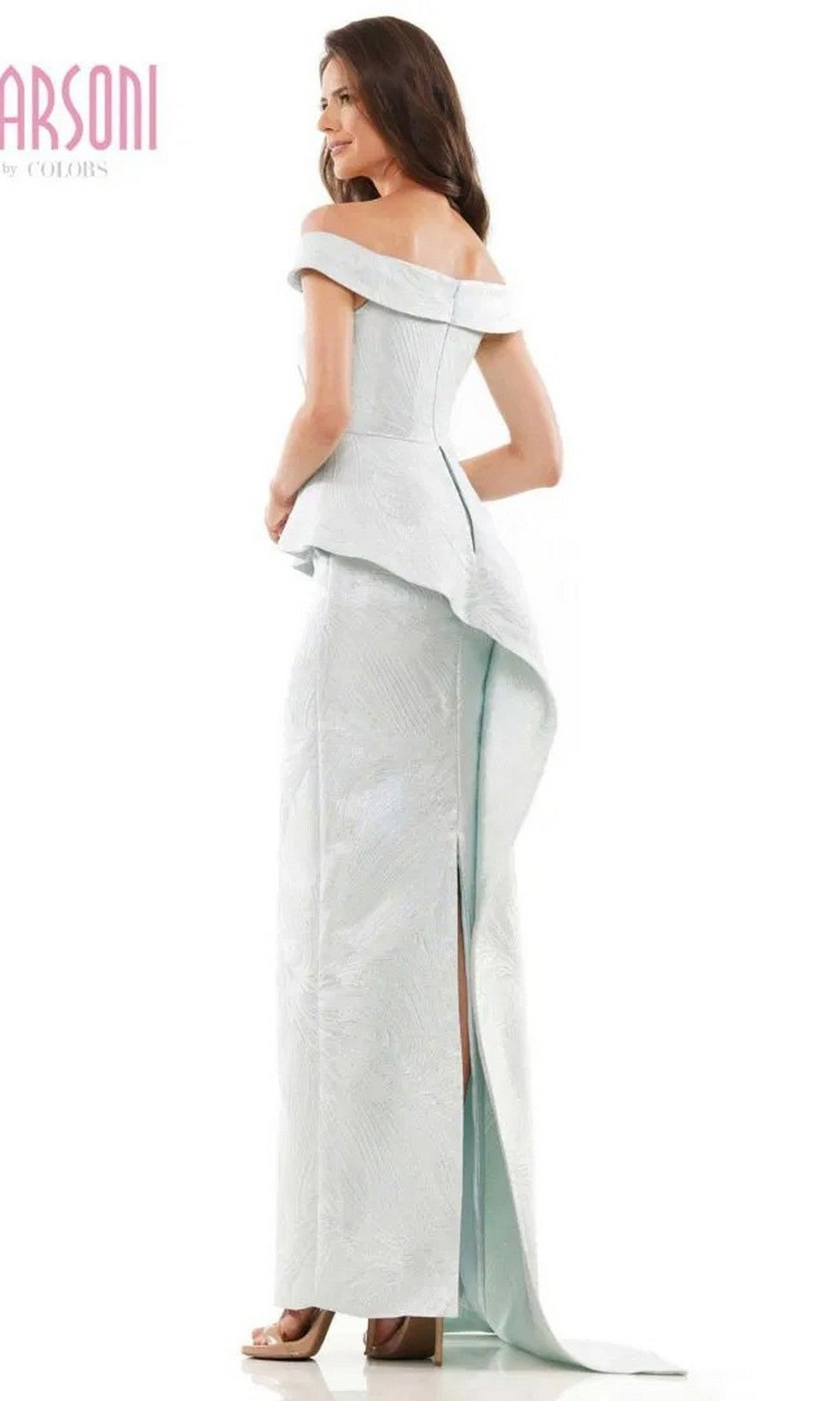 A woman in the Marsoni MV1225 long formal dress, featuring light blue jacquard fabric, off-shoulder sleeves, a peplum waist, and a back slit, stands on high heels facing away from the camera.